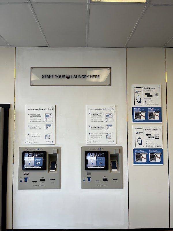 Two Laundroworks payment kiosks under a Start Your Laundry Here sign, with instructions in English and Spanish